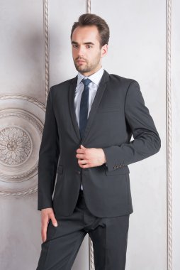 Duvarın önünde duran genç adam.