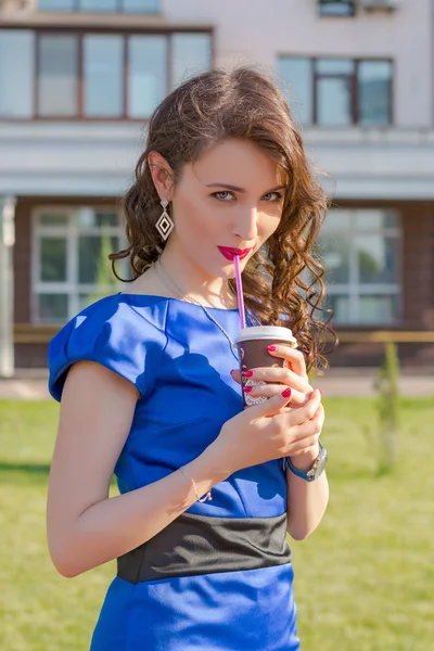 Красивая девушка пьет кофе перед зданиями в Eur — стоковое фото