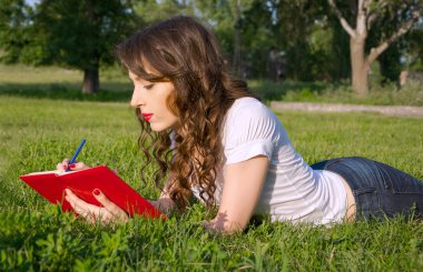 bir not defteri ve kalem çim bir yaz parkta kızla