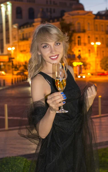 Девушка с бокалом шампанского ночью — стоковое фото