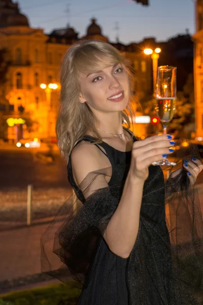 Девушка с бокалом шампанского ночью — стоковое фото