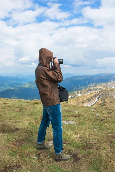 Fotograf je fotografování krajiny na vrcholu hory. — Stock fotografie