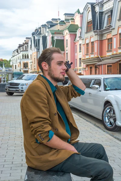 A young man sitting on a bench — Stock Photo, Image