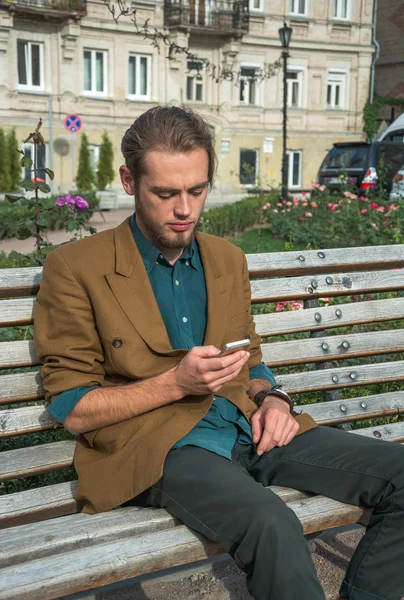 A young man sitting with cell phone — Stock Photo, Image