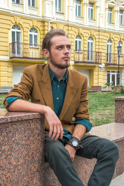 A young man sitting on a bench — Stock Photo, Image
