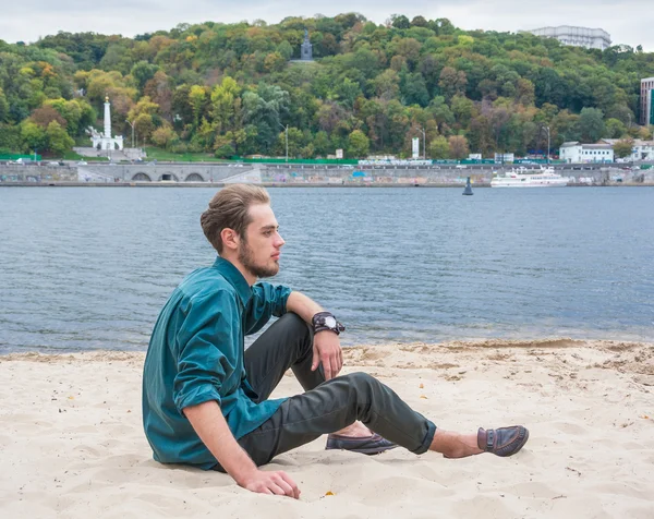 Le jeune homme est assis près d'une rivière — Photo