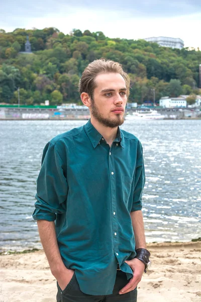 Young man is standing near a river — Stock Photo, Image