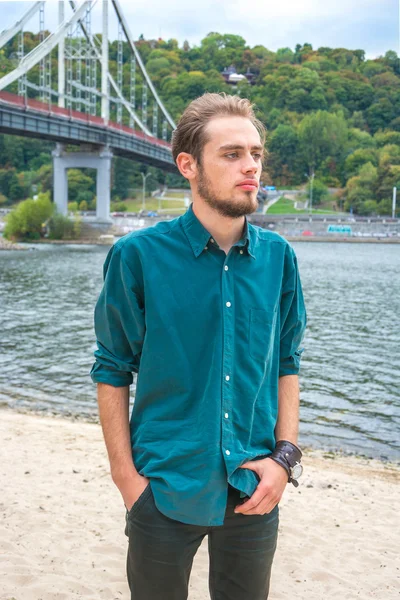 Young man is standing near a river — Stock Photo, Image