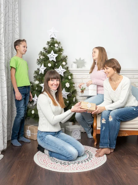 Friends giving presents at the Christmas tree. — Stock Photo, Image