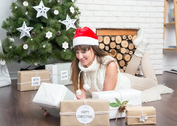 Das Mädchen hält ein Geschenk vor dem Weihnachtsbaum — Stockfoto