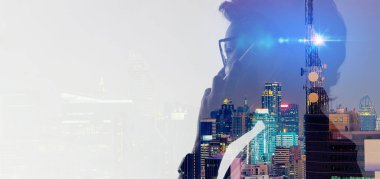 Akıllı telefon ve telekomünikasyon kulesi kullanan Asyalı kadının akıllı şehir arka planında 5G cep telefonu ağ anteniyle iki kez görüntülenmesi