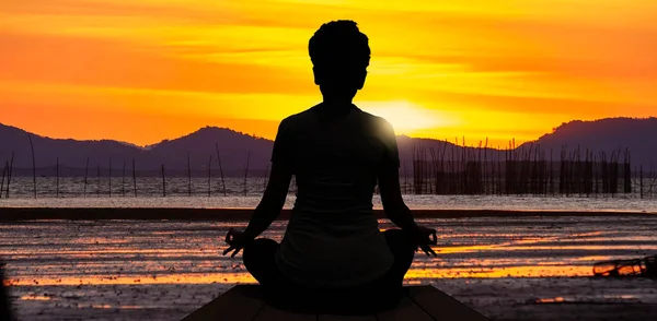 The silhouette of woman sitting yoga alone,Relax and meditate,mental health concept with nature spiritual.