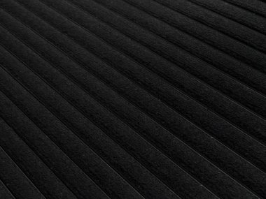 Close-up of black ribbed carpet surface showing linear grooves and soft fabric texture. Ideal for use in interior design