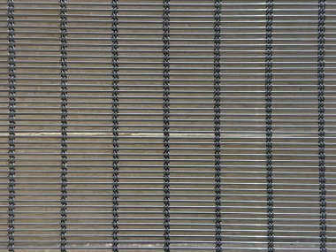 Endüstriyel ya da mimari tasarım için kullanılan metal tel örgülerin yakın çekimi. Paslanmaz çelik malzeme geometrik doku ve modern metalik yüzey arkaplanı oluşturur.