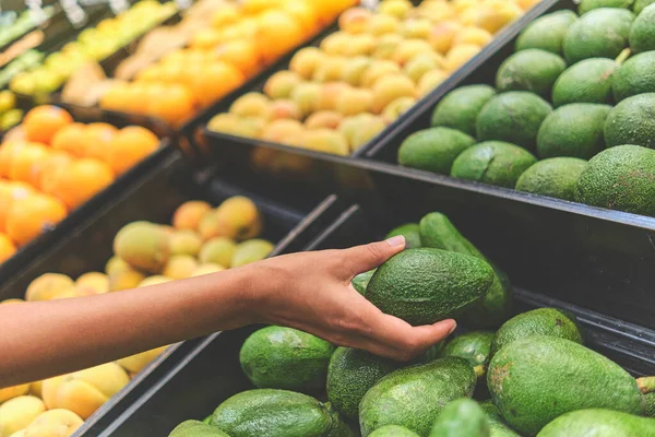 Markette Avokado Seçen Genç Kadın. Sağlıklı gıda, biyolojik, vejetaryen, diyet kavramı. Seçici odak.