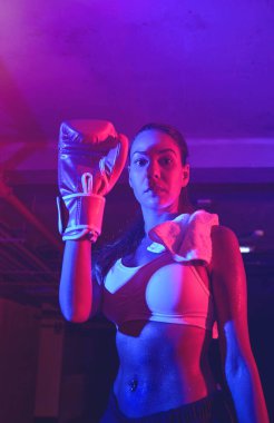 Güzel kadın boksör eğitimi, kırmızı boks eldivenleri, kırmızı ve mavi ışıklı ring, endüstriyel spor salonu, neon ışıklar. seçici odak