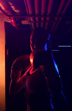 Siluet kadın boksör eğitimi, kırmızı boks eldivenleri, kırmızı ve mavi ışıklı ring, endüstriyel spor salonu, neon ışıklar. seçici odak