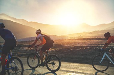 Gün batımı otoyolunda bisiklet süren bir grup bisikletçi arkadaş, gün batımı bisiklet yarışması
