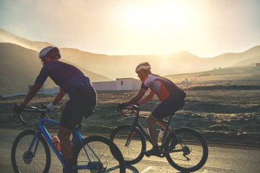 Gün batımı otoyolunda bisiklet süren bir grup bisikletçi arkadaş, gün batımı bisiklet yarışması