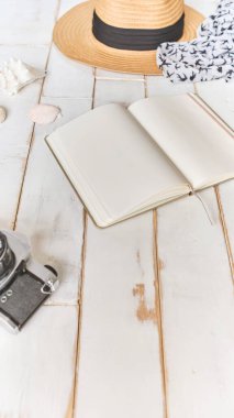 Analog bir kamera ve ahşap bir masanın üzerinde bir defter, fotoğrafçının elleri eski bir film kamerasını ahşap arka planda, seyahat kıyafetinde, konsept yolculuğunda tutuyor.