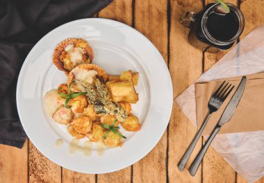 Peru yemeği: Sarımsaklı ve otlu soteli karides, ahşap masa, yanında mor mısır suyu ile birlikte beyaz bir tabakta servis ediliyor.