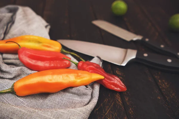 Peruvian peppers with other ingredients on wooden table and knife (limo pepper, ecabeche pepper and lemon)) top view. Selective focus