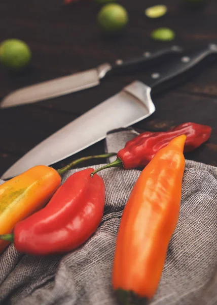 Peruvian peppers with other ingredients on wooden table and knife (limo pepper, ecabeche pepper and lemon)) top view. Selective focus