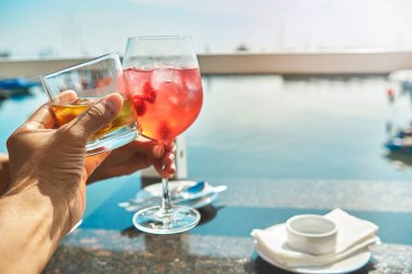 Couple toasting the beginning of summer at marina, cheers cups and glass, summer concept.