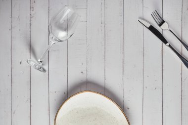 Boş tabaklar, çatallar ve beyaz ahşap arka planda bir bardak şarap. Üst Manzara. Modellemeyi Göster