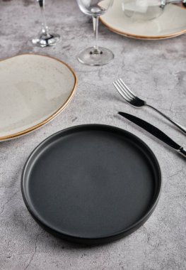 Boş tabaklar, çatallar ve gri beton arka planda bir bardak şarap. Üst Manzara. Modellemeyi Göster