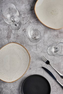Boş tabaklar, çatallar ve gri beton arka planda bir bardak şarap. Üst Manzara. Modellemeyi Göster