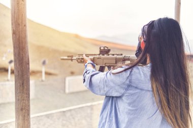 Kadın, tetikçiyi güçlendirmiş, tüfeği hedefe doğrultmuş. Seçici Odaklanma