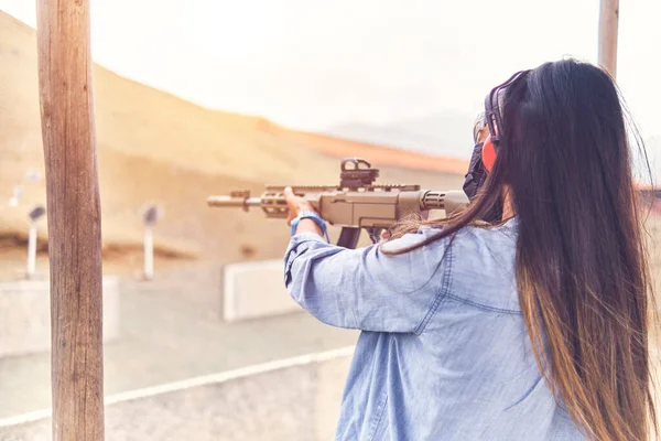 Mulher com poder de tiro apontando rifle de assalto ao alvo. Foco seletivo — Fotografia de Stock