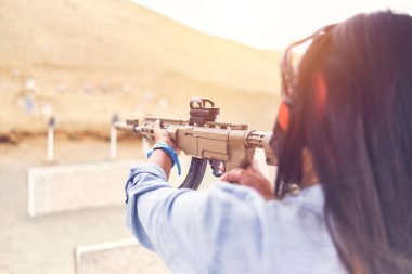 Kadın, tetikçiyi güçlendirmiş, tüfeği hedefe doğrultmuş. Seçici Odaklanma