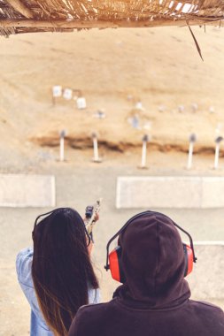 Kadının stres atması, eğitmenin silahlı kadına yardım etmesi.