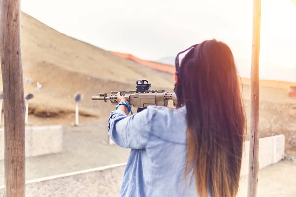 Mulher com poder de tiro apontando rifle de assalto ao alvo. Foco seletivo — Fotografia de Stock