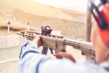 Kadın, tetikçiyi güçlendirmiş, tüfeği hedefe doğrultmuş. Seçici Odaklanma