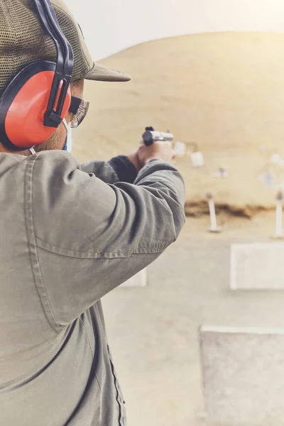 Man with hand gun aiming at shooting range and releasing stress. Selective Focus — Stock Photo, Image