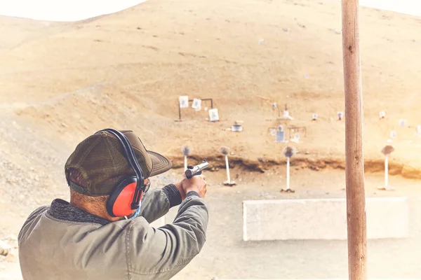 Homem com pistola apontando para o alcance de tiro e liberando o estresse. Foco seletivo — Fotografia de Stock