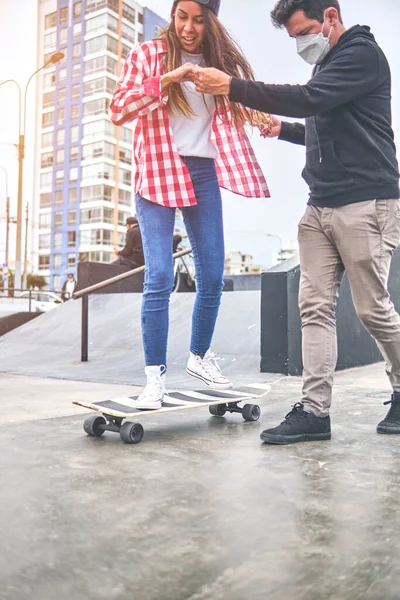 Gelukkige jonge vrouw leren met haar instructeur op de skateboard helling. Zomertijd. — Stockfoto