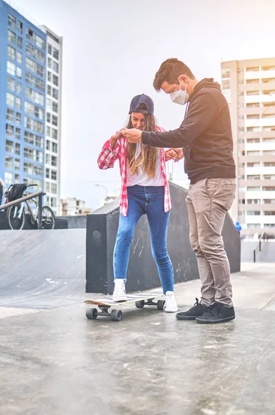 Gelukkige jonge vrouw leren met haar instructeur op de skateboard helling. Zomertijd. — Stockfoto