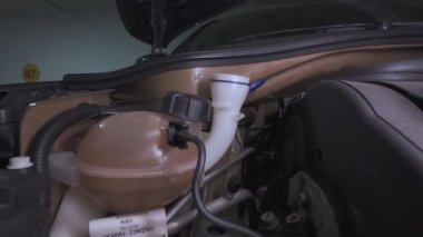 Araba deposuna mavi cam temizleme sıvısı döken bir tamirci.