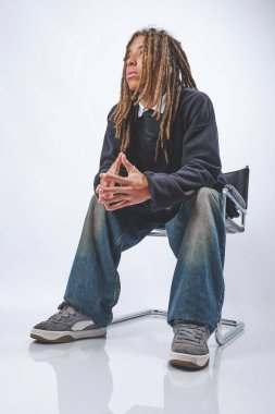 Sandalyeye oturmuş, elleri kelepçeli, düşünceli genç bir adam.