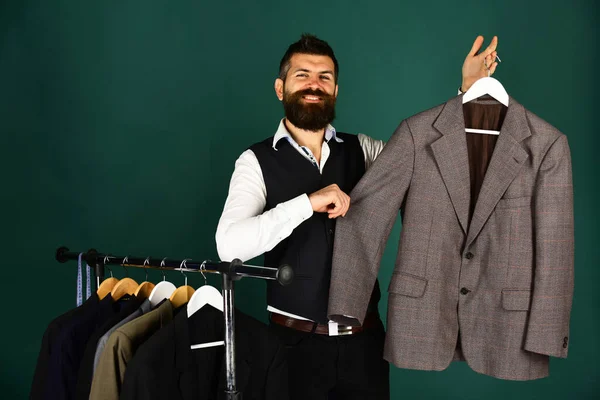 Designer presents jacket on clothes hanger. Man with beard