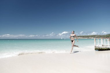Tazelenmiş ve neşeli. Kız bikinisi okyanus kumsalında dalgalanır. Lüks tropik okyanus plajı tatil beldesi. Seksi kadın vücudu okyanus beyaz kumsalı Antigua 'yı rahatlatır. Sihirli turkuaz gölün içinden koş