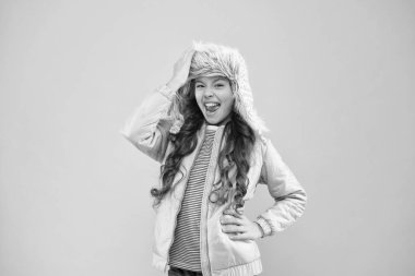 Kış moda konsepti. Soğuk hava için sıcak şapka. Sahte kürk trendi. Uzun kıvırcık saçlı kız, pembe kulaklıklı kürk şapka takıyor. Yumuşak tüylü aksesuar. Çocuk uzun saçlı yumuşak kürk şapkalı Yumuşaklığın tadını çıkar