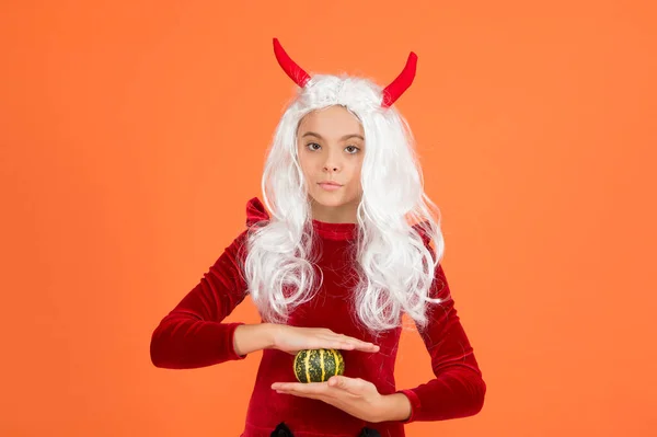 one little thing. kid hold pumpkin. traditional holiday food and autumn harvest. childhood happiness. teen girl ready to celebrate costume party. happy halloween. child in devil horns and white hair