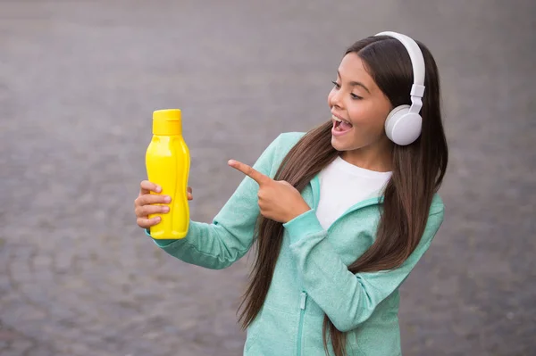 Ευτυχισμένη έφηβη που δείχνει με το δάχτυλο το μπουκάλι με το νερό που πάει για ποτό, αναψυκτικό — Φωτογραφία Αρχείου