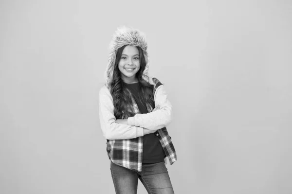 Mantener fuera el frío en invierno. Pequeña sonrisa de niña en piel sintética sombrero de fondo amarillo. Niño feliz desgaste moda accesorio de invierno. Pequeño modelo de moda disfrutar del estilo de invierno. Dar toque de elegancia al atuendo de invierno — Foto de Stock