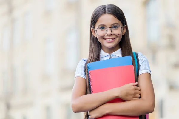 Šťastné malé dítě úsměv v brýlích drží školní knihy venku, znalosti, kopírovací prostor — Stock fotografie